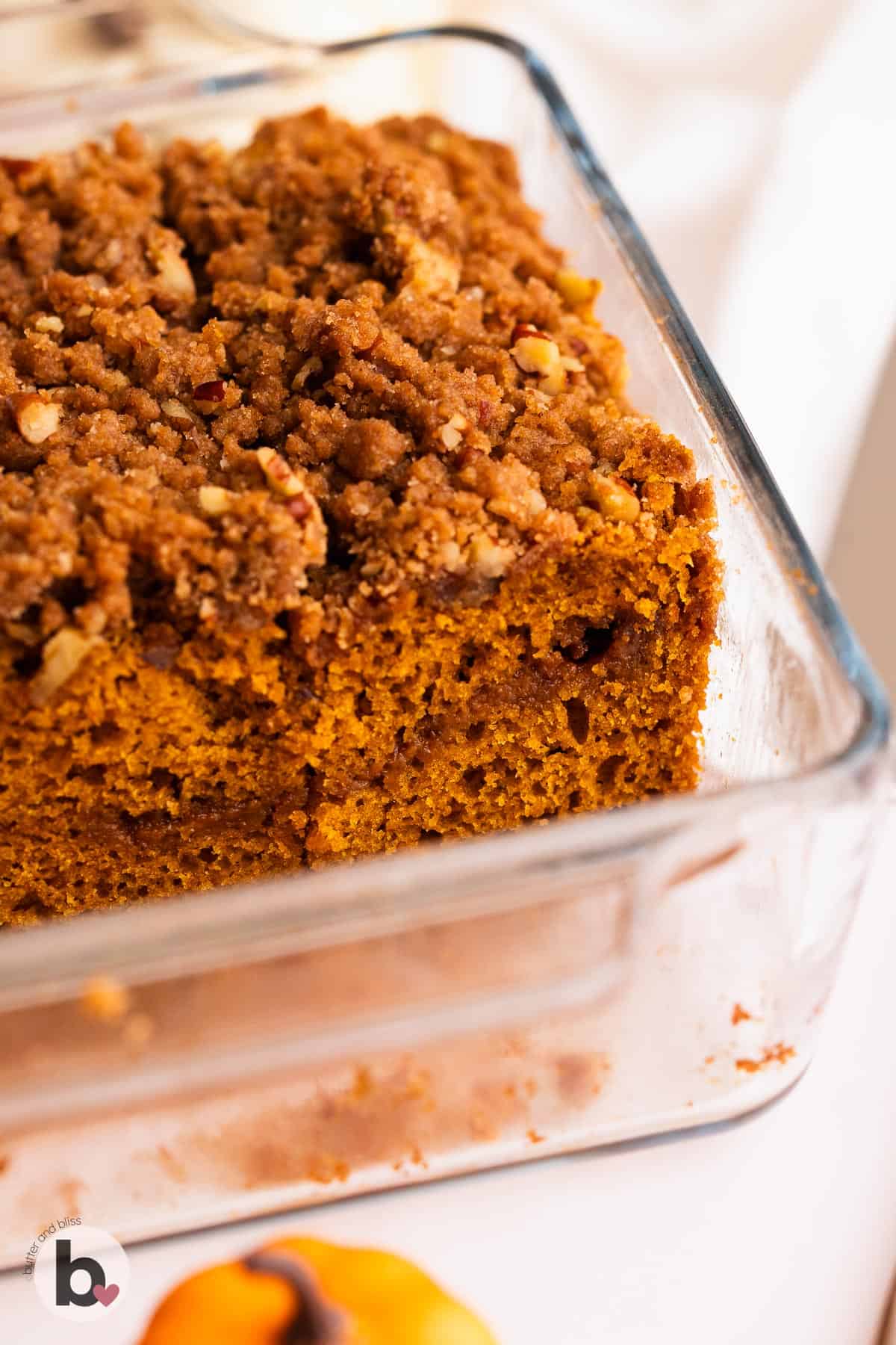 Small pumpkin streusel coffee cake in pan revealing cinnamon swirl center.