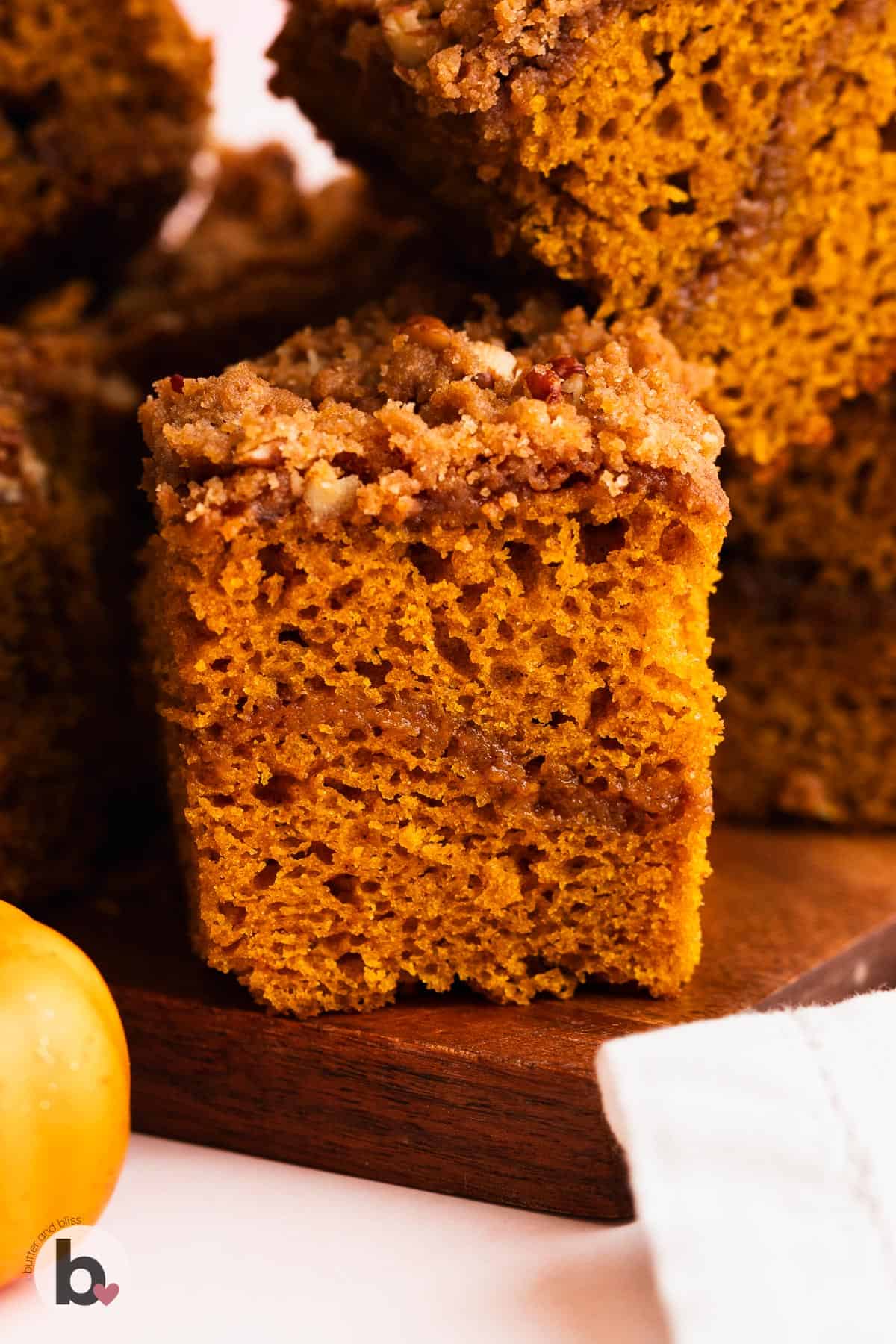 Single slice of pumpkin streusel coffee cake on a wood cutting board.