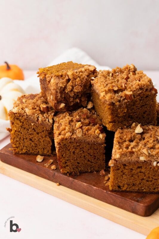 Pumpkin almond streusel bread cut into squares and stacked on a wood cutting board.