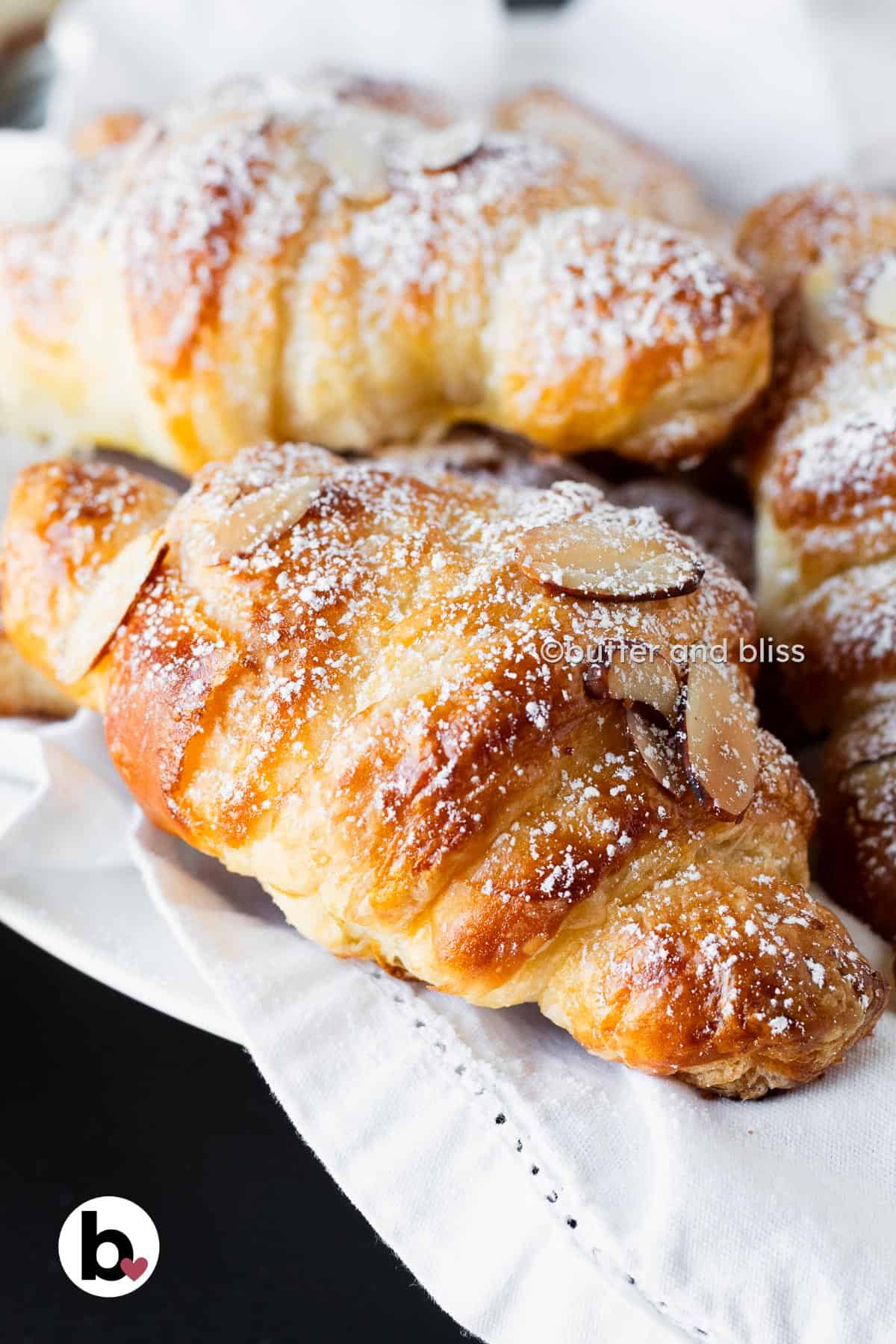 Butter and Bliss almond croissants dusted in powdered sugar in a basket.