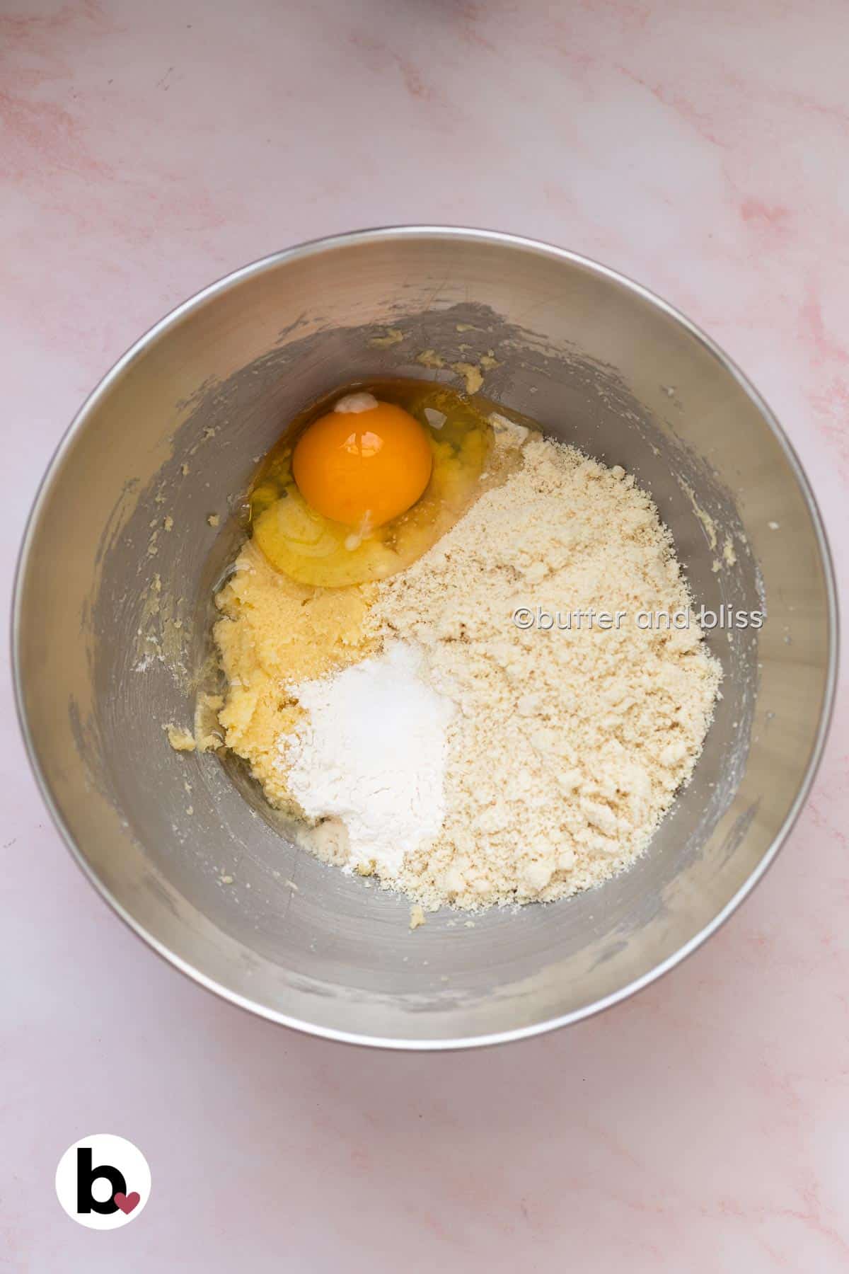 Almond flour and egg added to creamed butter in a mixing bowl.