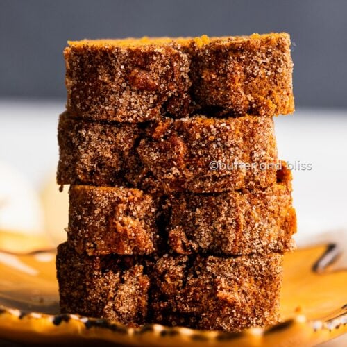 Slices of Butter and Bliss cinnamon sugar pumpkin bread mini loaf stacked on a fall plate.