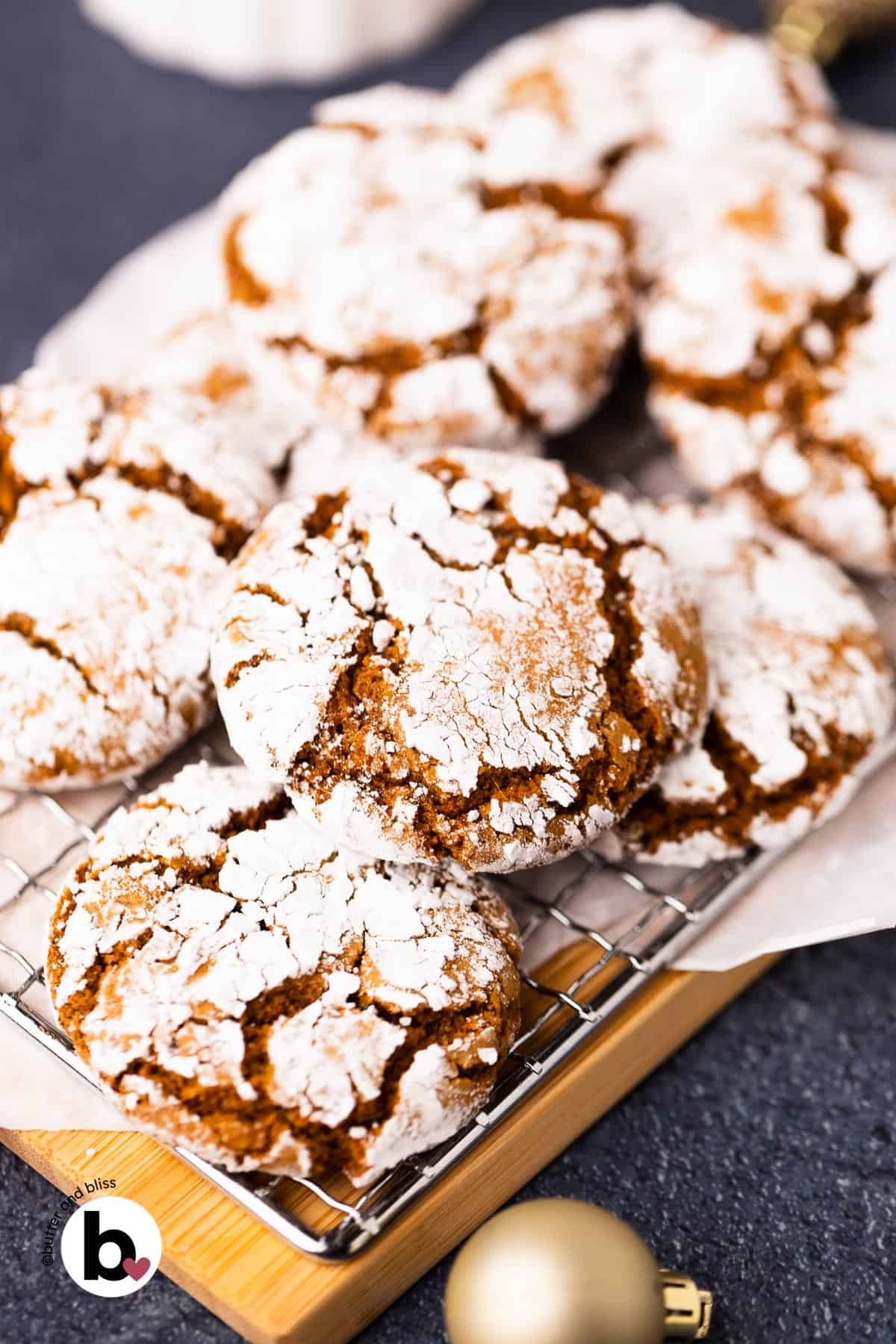 Freshly baked small batch of molasses crinkle cookies piled on a wood plate.