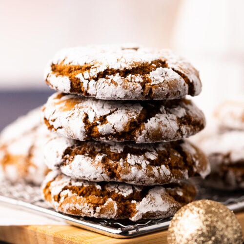 A stack of chewy molasses crinkle cookes on a wood plate.
