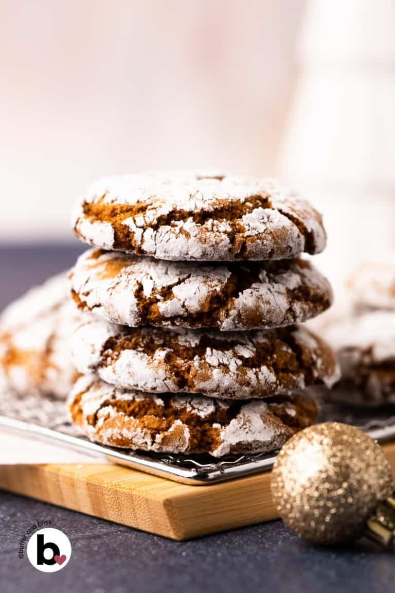 A stack of chewy molasses crinkle cookes on a wood plate.