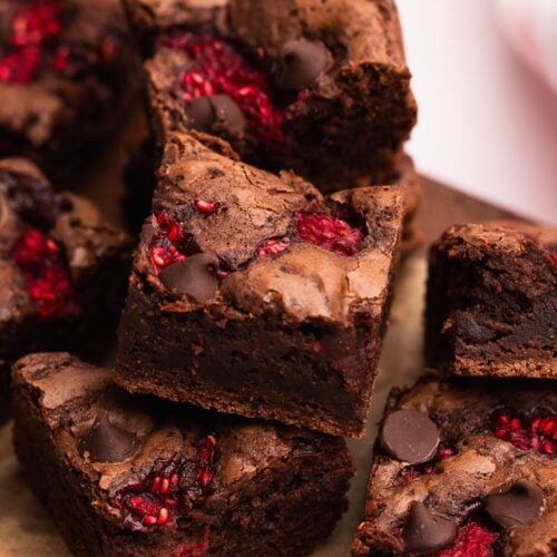 Small batch raspberry brownies cut into squares and piled on a wood cutting board.