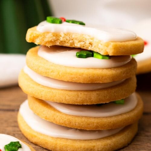 A short stack of holiday decorated marshmallow sugar cookies with a bite out of the top cookie.