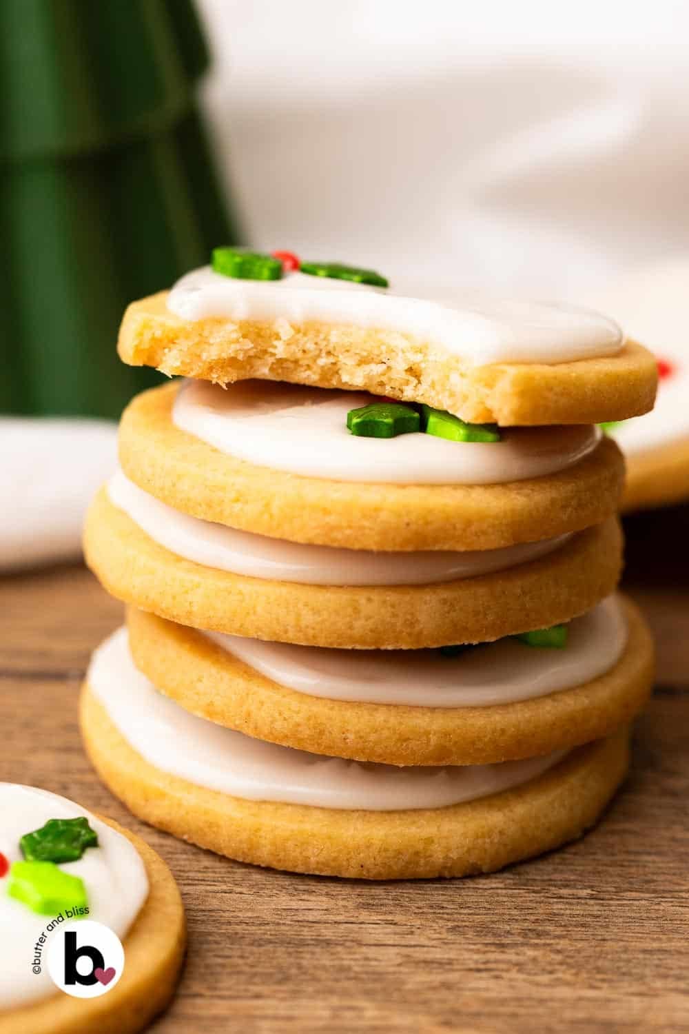 A short stack of holiday decorated marshmallow sugar cookies with a bite out of the top cookie.
