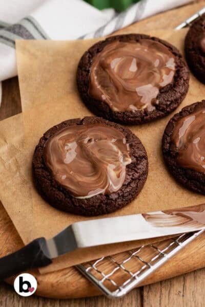 Melty andes mint candies spread on top of chocolate cookies on parchment paper.