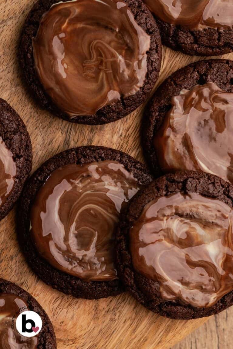 Chocoalte andes cookies with a melty candy swirled on top on a wood plate.