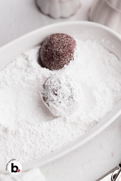 Red velvet cookie dough balls rolled through powdered sugar.