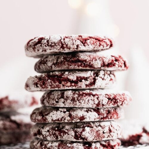 A stack of small batch red velvet crinkle cookies on a wood cutting board.