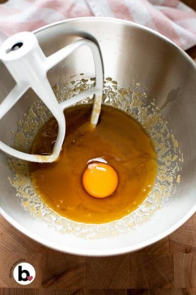 Egg added to mixed butter and sugar in a mixing bowl, ready to be mixed.