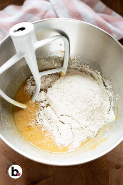 Dry ingredients sprinkled over wet ingredients in a mixing bowl, ready to be mixed.