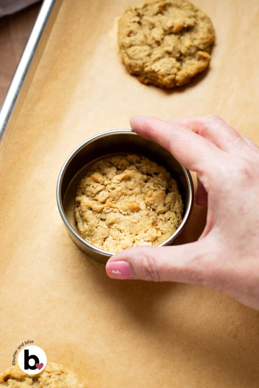 Fresh baked oatmeal cookie being swirled in the middle of a round cookie cutter to get a perfectly round cookie.