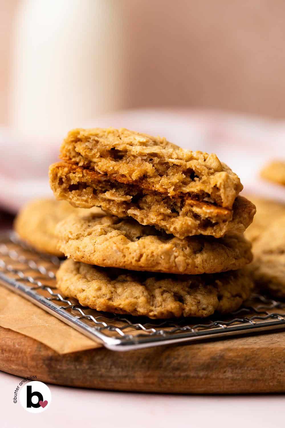 Small stack of oatmeal cookies with one cut in half on top, revealing the chewy center.