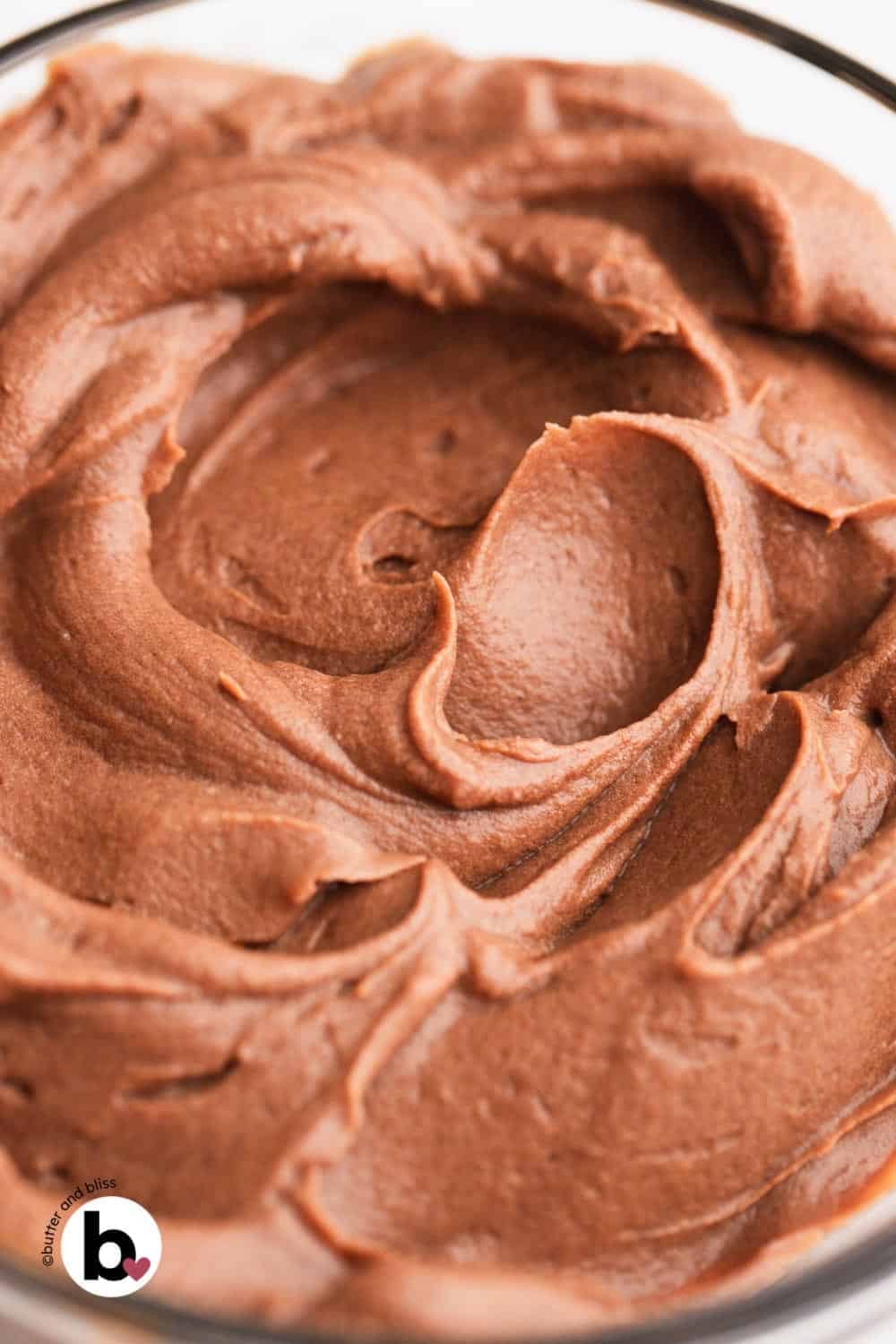 Soft swirls of chocolate whipped ganache in a mixing bowl.