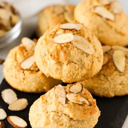 A small batch of almond maple cookies piled onto a black plate.