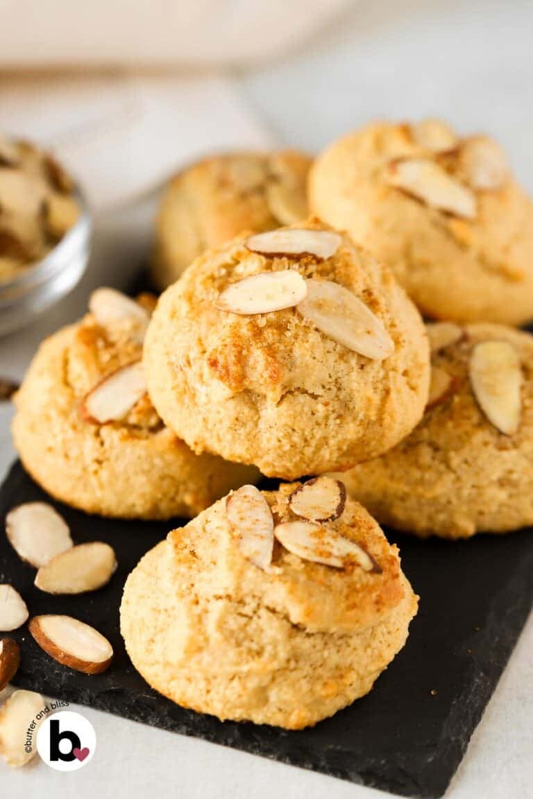 A small batch of almond maple cookies piled onto a black plate.