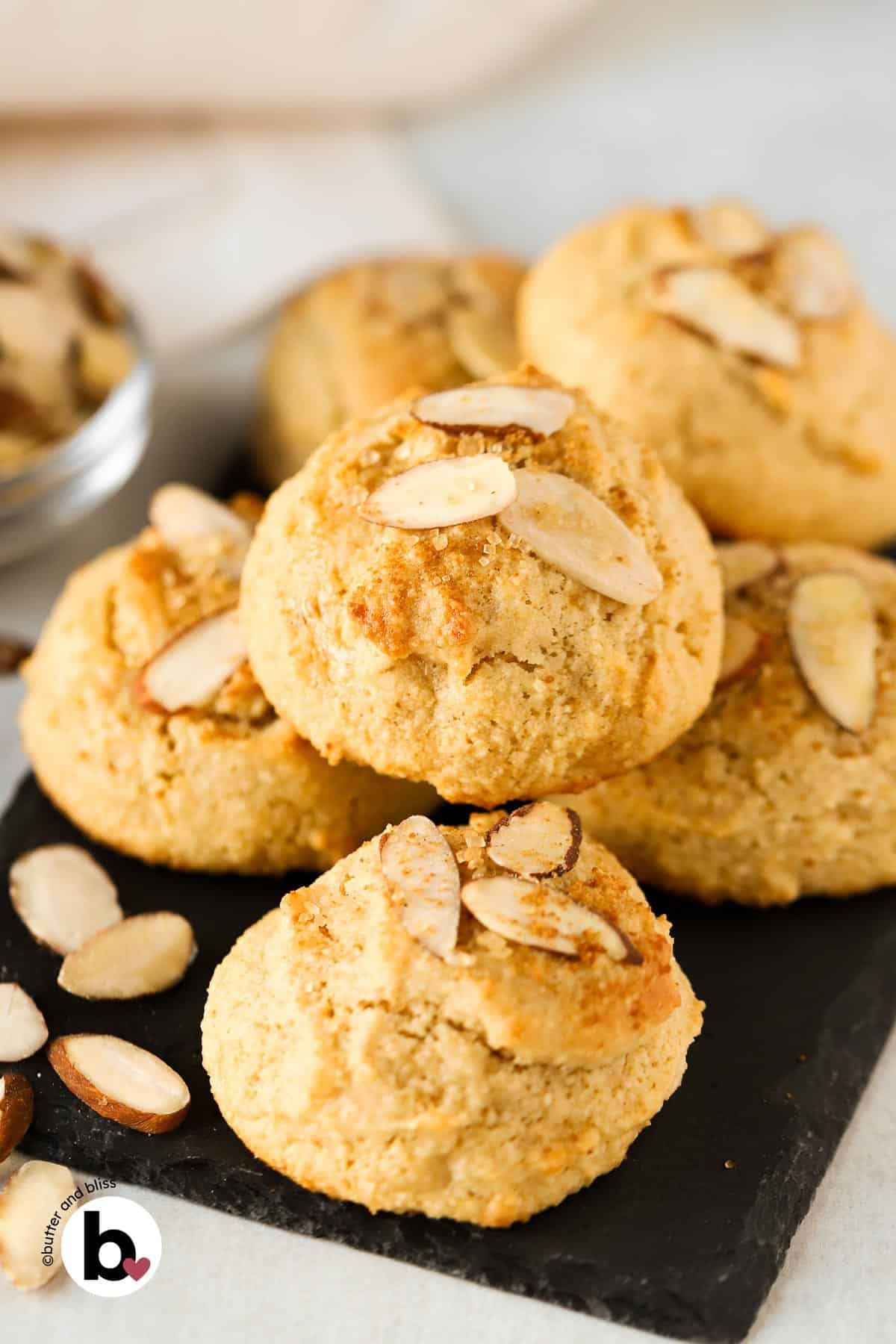 A small batch of almond maple cookies piled onto a black plate.