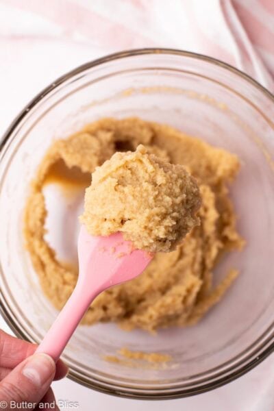 Thick almond flour and maple syrup cookie batter on a pink spatula.