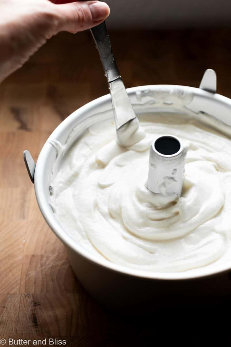 Hand running a knife through fluffy angel food cake batter.