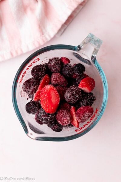 Frozen mixed berries in a liquid measuring cup.