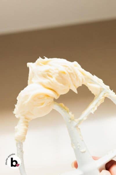 Fluffy cream cheese buttercream frosting on a mixing whisk.