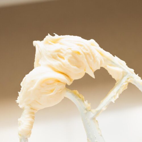 Fluffy cream cheese buttercream frosting on a mixing whisk.