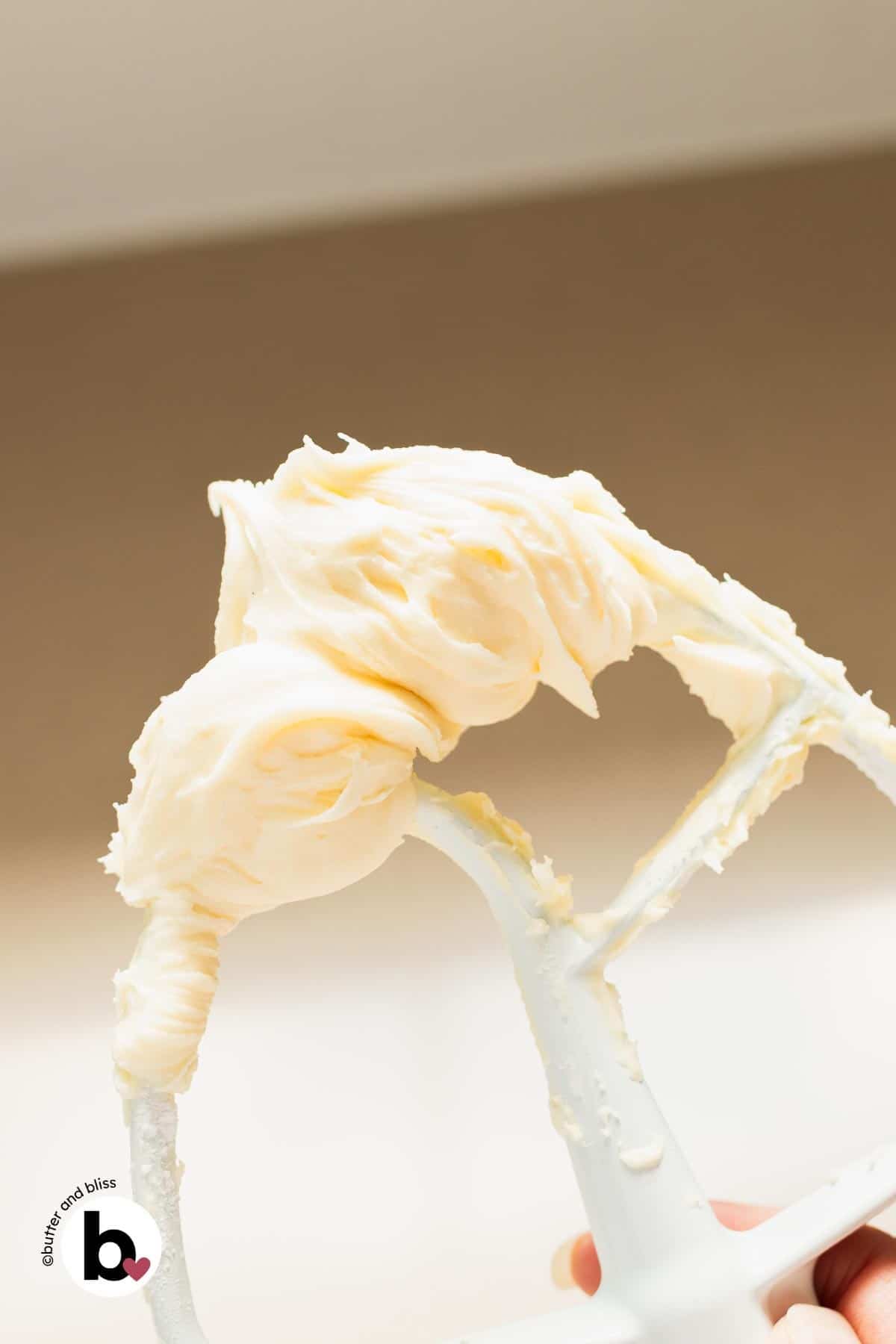 Fluffy cream cheese buttercream frosting on a mixing whisk.