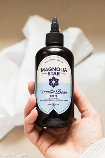 Hand holding a jar of vanilla bean paste.