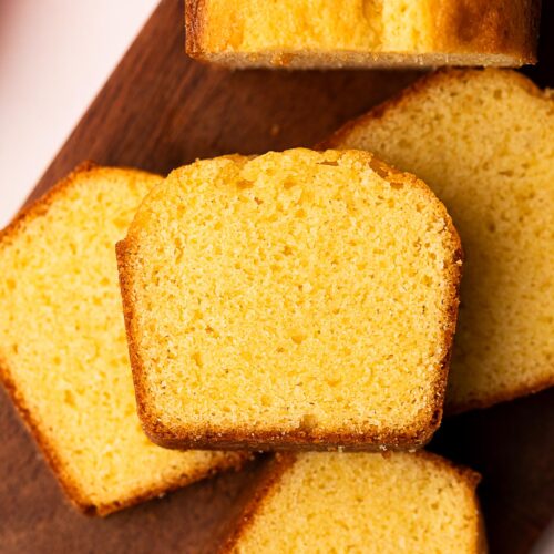 A small pound cake cut into slices and arranged on a cutting board.