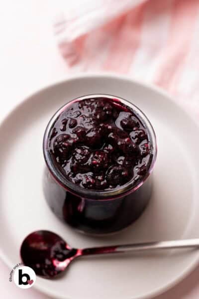 Raspberry and blueberry compote in a small jar with a spoon.