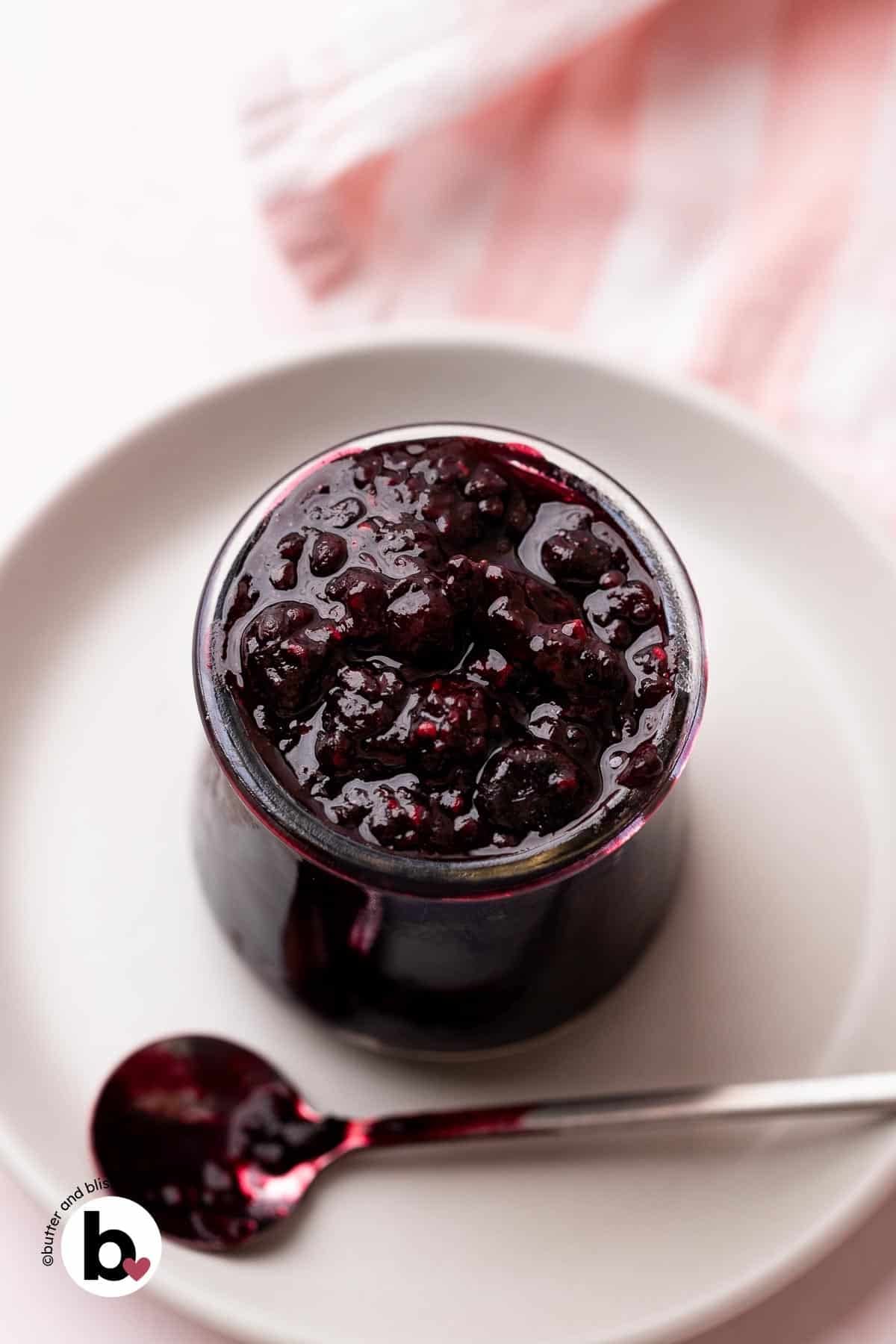 Raspberry and blueberry compote in a small jar with a spoon.