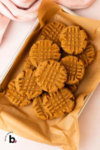 Small batch of chewy peanut butter cookies piled on a small baking sheet.