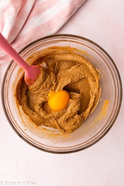 Egg yolk added to creamed butter and sugar in a mixing bowl.