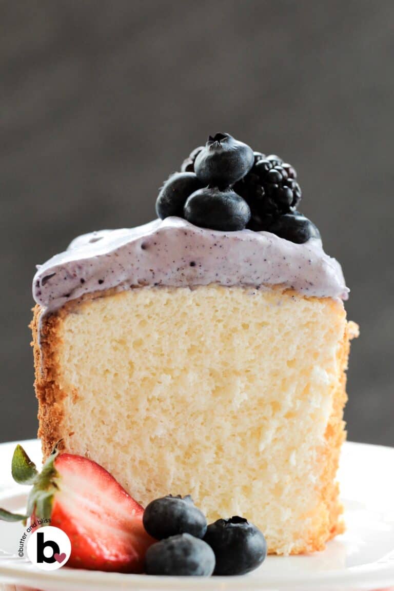 A slice of fluffy angel food cake with fresh berries and whipped cream on a plate.
