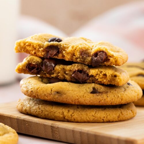 Stack of chocolate chip cookies with one cut in half revealing chewy inside.