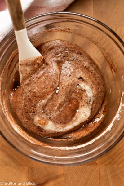 Powdered sugar and cocoa powder being folded into whipped egg whites.