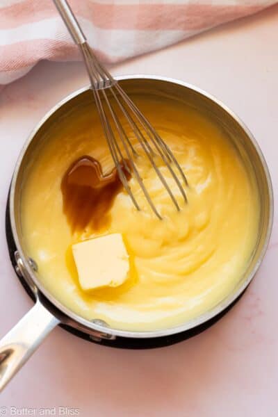 Butter and vanilla added to warm pastry cream in a saucepan.