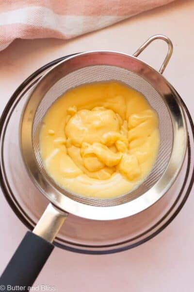 Pastry cream being strained into a bowl.