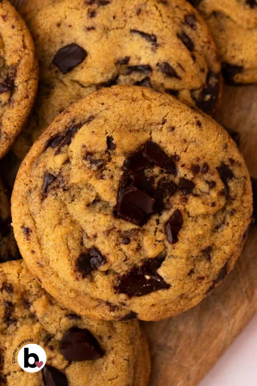 Brown butter chocolate chip cookie in a pile with large chocolate chunks.