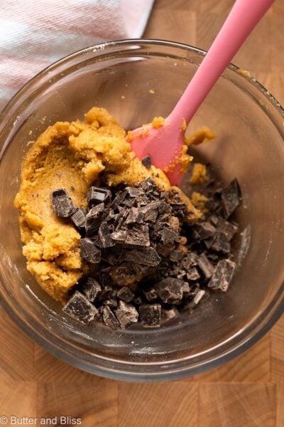 Chocolate chunks added to cookie dough in a mixing bowl.