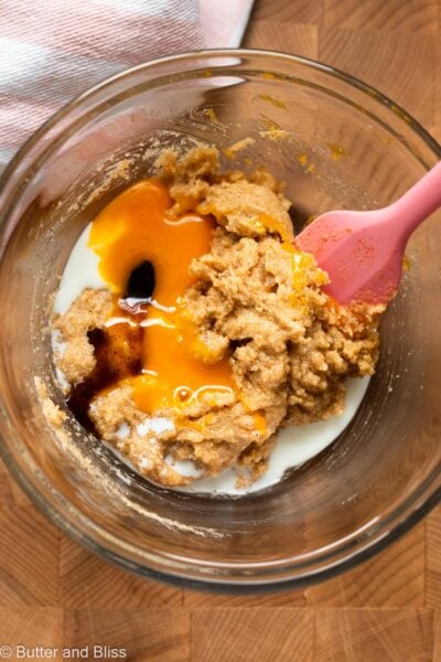 Egg yolk added to creamed butter and sugar in a mixing bowl.