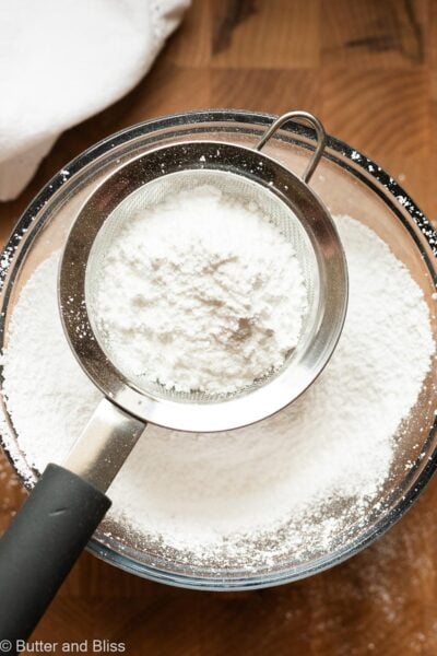 Powdered sugar being sifted into a mixing bowl.