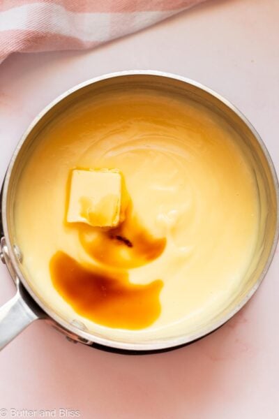Butter and vanilla added to vanilla pudding in a pan.