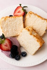 Slices of a mini angel food cake on a plate with fruit.