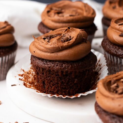 Cupcake liner peeled back on a moist chocolate frosted cupcake.