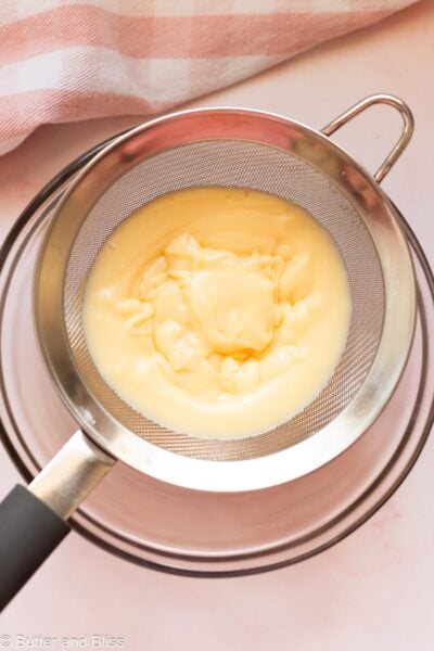 Vanilla pudding strained over a mixing bowl.
