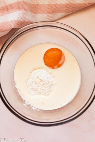 Egg yolk and cornstarch in a bowl with cream.